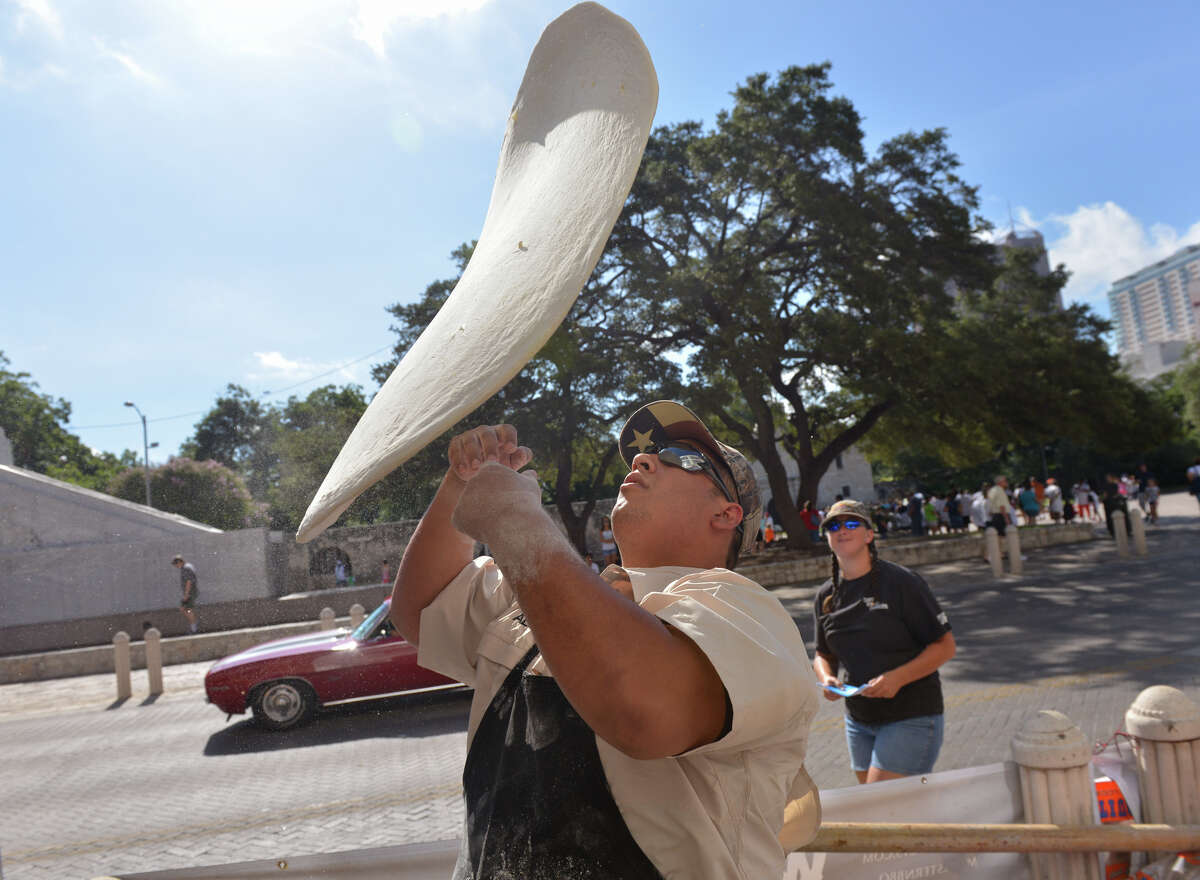 Alex Rymers of Dirt Road Cookers tosses dough in front of the Guinness museum during an attempt to snag the Guinness World Record for the "largest commercially available" pizza on Saturday, Aug. 3, 2013. The pizza was 92 1/2 inches in diameter and weighed about 88 lbs.