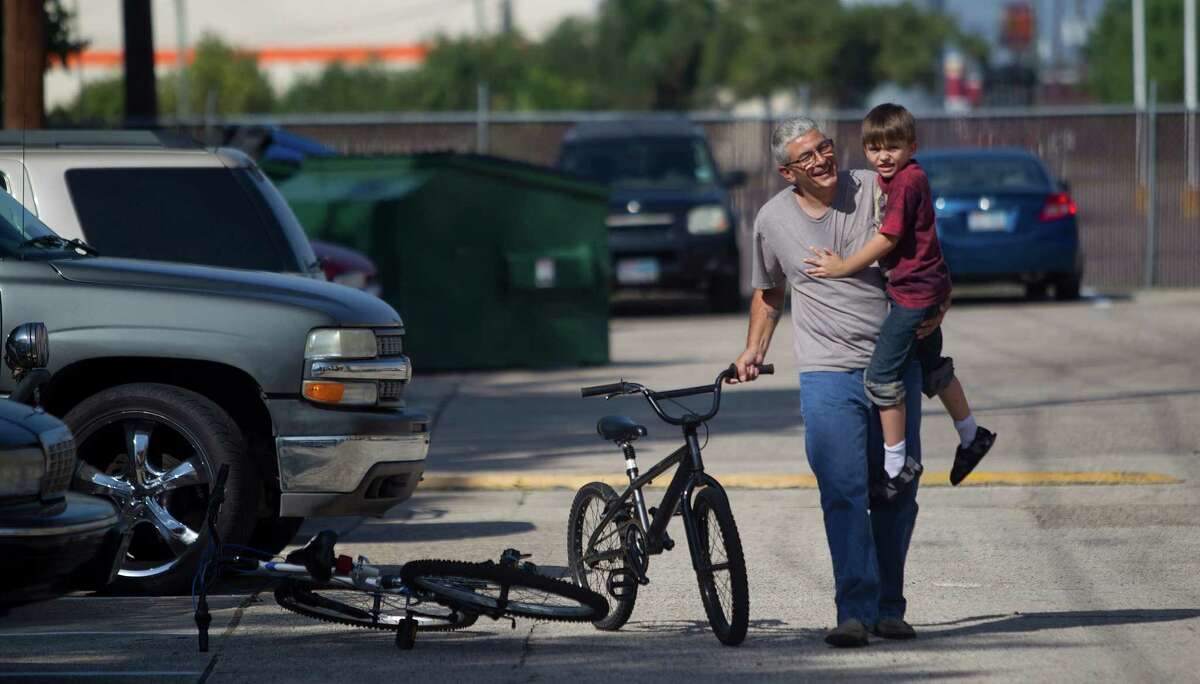 "You'll be all right," Frank Lowrance says as he comforts his son, Noah, who crashed on his bike at their home in Spring. In Harris County, single dads like Lowrance head nearly 39,500 household, according to the census.
