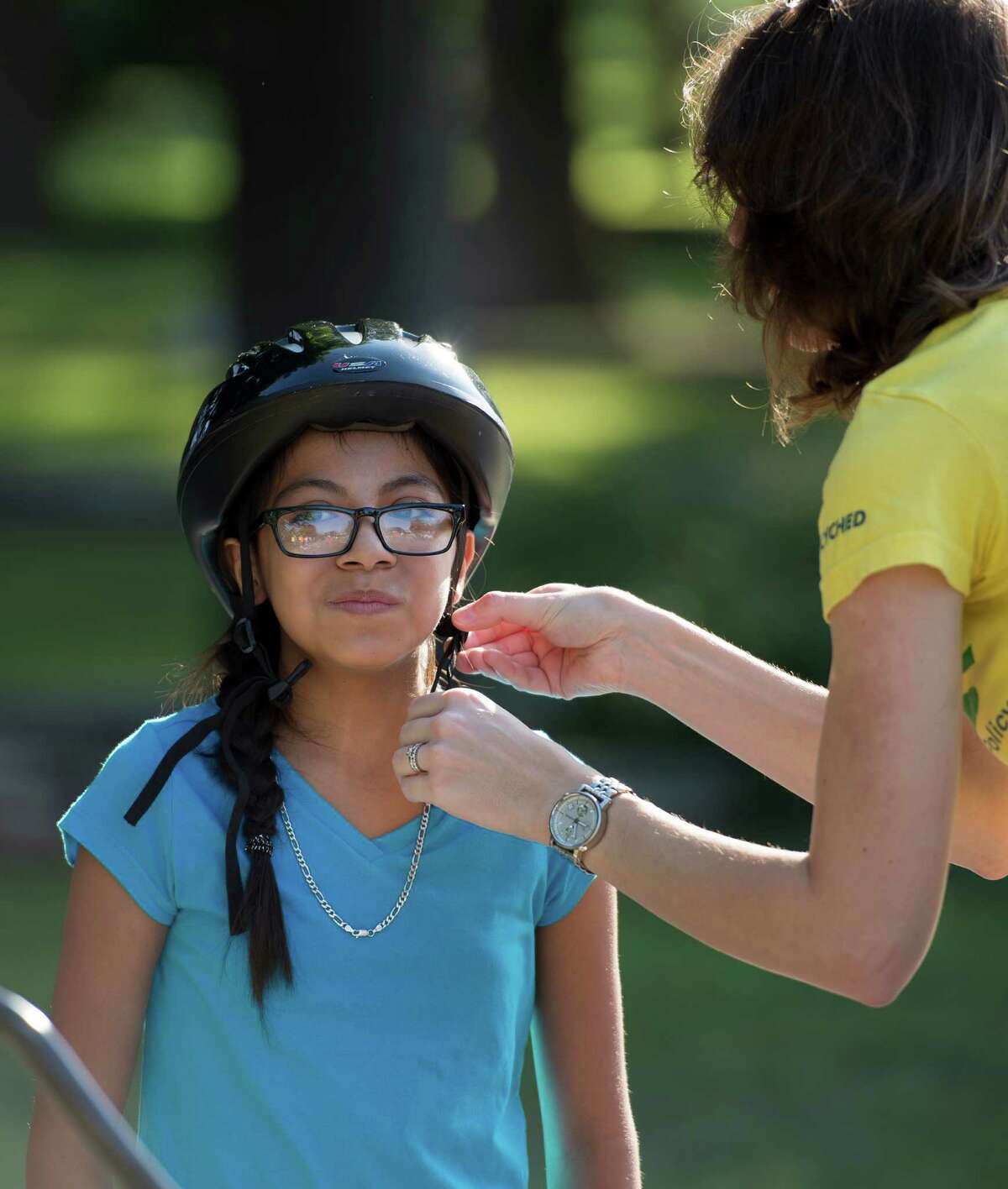 Diamond Hernandez, 13, gets some help adjusting her helmet from Allison Blazosky before a bicycle ride organized by Roll Models and the San Antonio Housing Authority, Saturday, July 13, 2013, in San Antonio. Roll Models is a program that helps kids and families bike to areas outside of their own neighborhoods. (Darren Abate/For the Express-News)