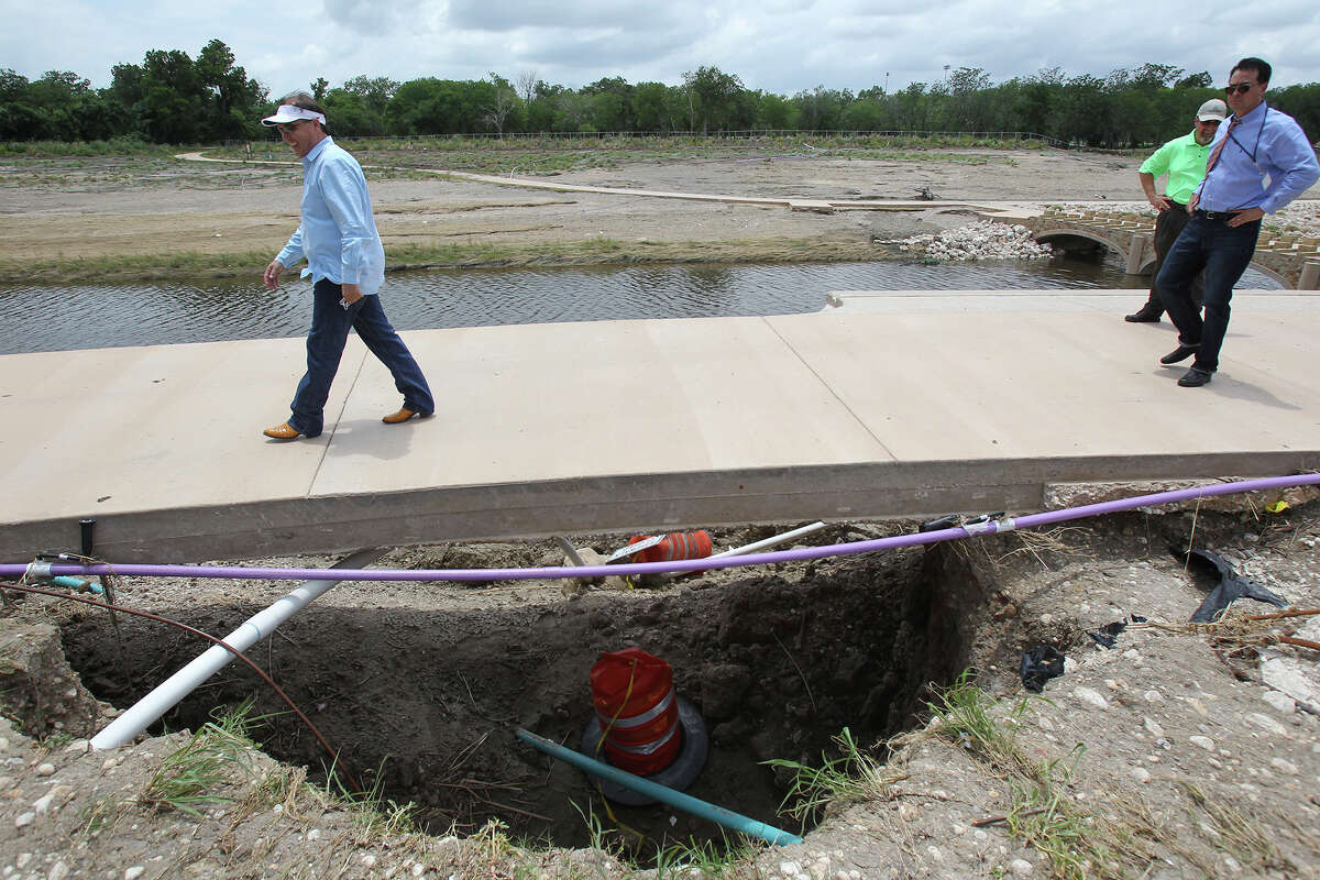 County Commissioner Sergio Chico Rodriguez tests the strength of a washed out walkway as San Antonio River Authority officials tour the flood damaged Mission Reach area on May 30, 2013.