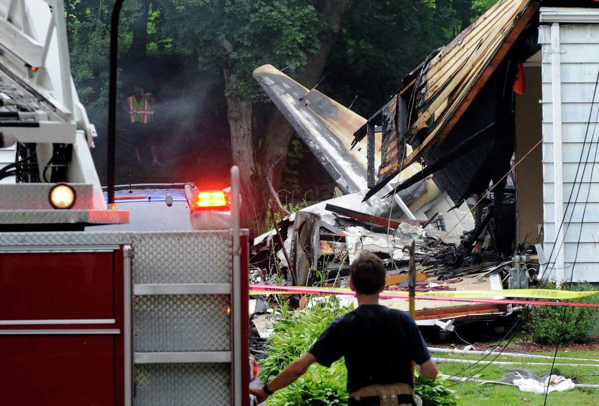 A firefighter surveys the scene of a small plane crash, Friday, Aug. 9, 2013, in East Haven, Conn. The multi-engine, propeller-driven plane plunged into a working-class suburban neighborhood near Tweed New Haven Airport, on Friday.