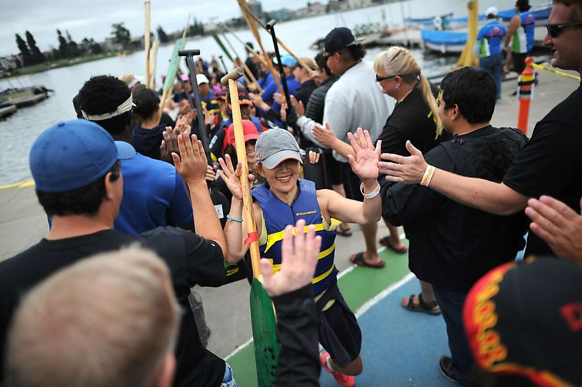 Racers are greeted with high fives after competing during the Dragon Boat Festival Races on Lake Merritt in Oakland, California Sunday, August 11, 2013.