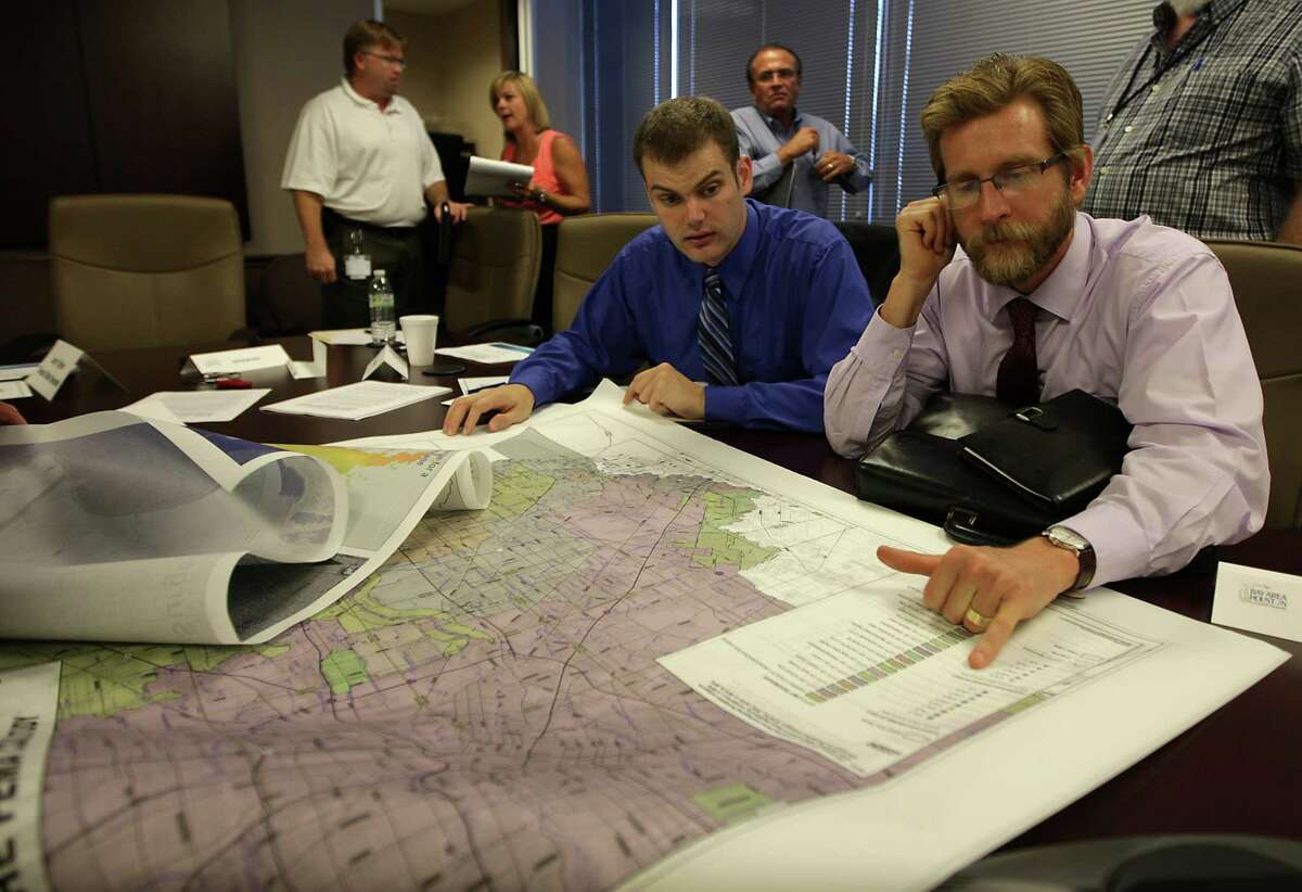 Stephen Cotten, left, and Jason Murasko, both University of Houston-Clear Lake assistant professors of economics, focus on new federal flood maps that put more homes into the flood plain at a meeting of coastal officials this month.