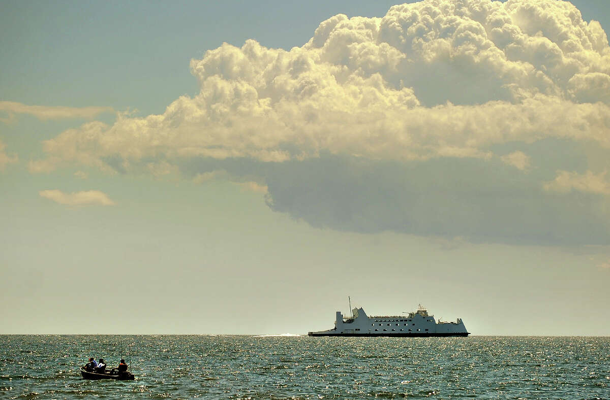 A trio of fishermen and the Port Jefferson ferry share the Sound under billowy clouds off Seaside Park in Bridgeport, Conn. on Tuesday, August 6, 2013.