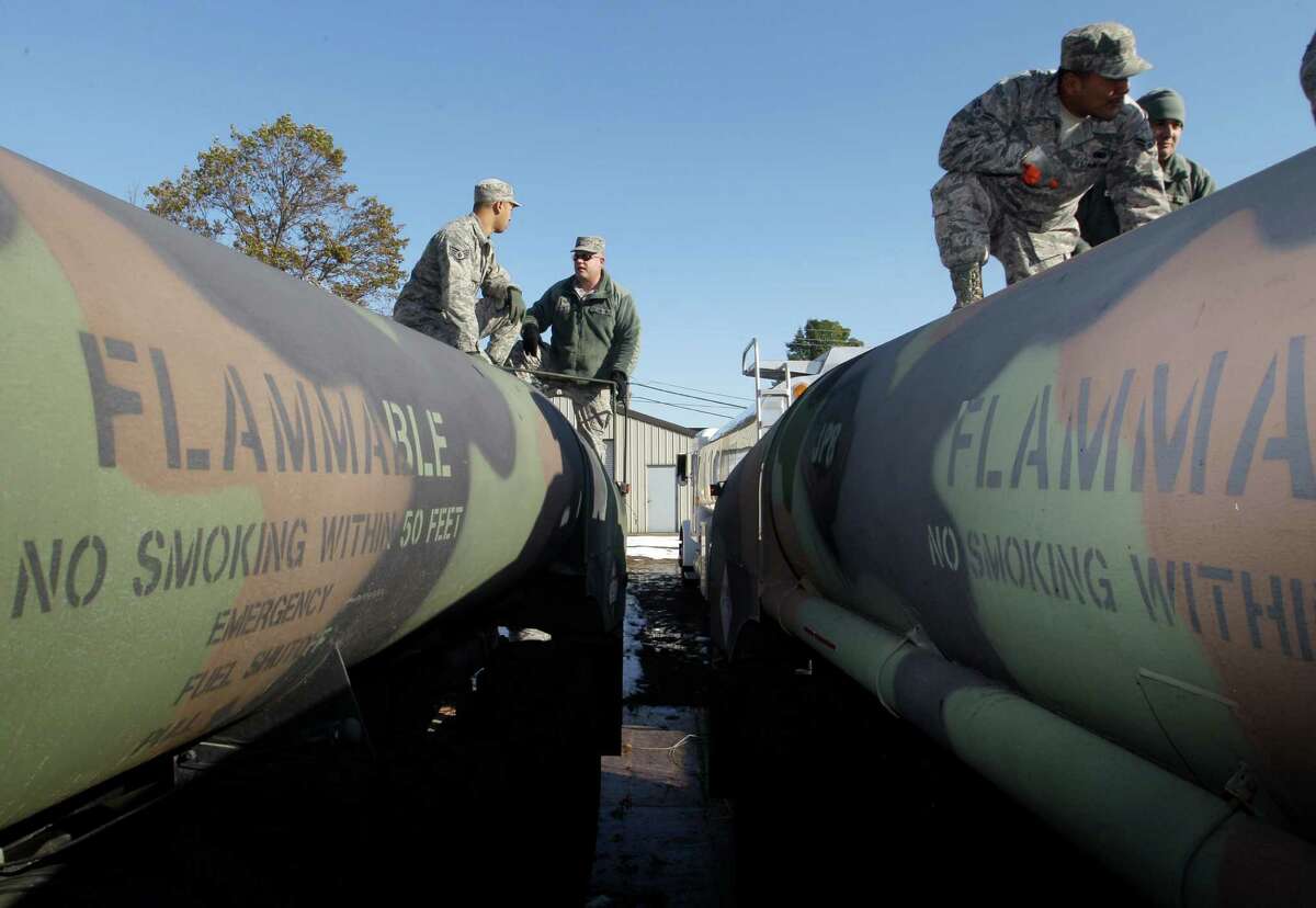 Army and Air National Guardsmen work on top of military tanker trucks in Freehold, N.J., Friday, Nov. 9, 2012, as they load fuel for delivery. Guard units have been deployed to help as the region continues to recover from last week's pounding by Superstorm Sandy. (AP Photo/Mel Evans)