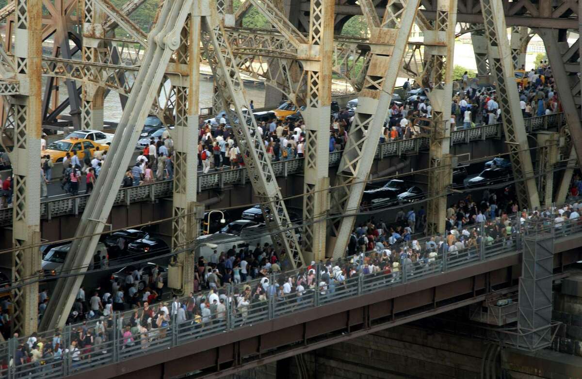 Pedestrians and traffic leaving downtown Manhattan crossing the Queensboro Bridge after the onset of the largest power blackout in American history, August 14, 2003. More than 50 million people were affected by the outage, in Toronto, Detroit, Cleveland and New York City.