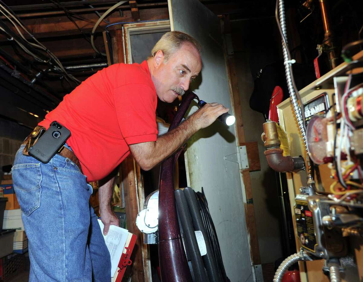 G. Neil Scott inspects the oil burner in the basement at a McArthur Lane home in Stamford, Tuesday, August 13, 2013. Scott is the owner of Scott and Scott Home Inspection Services Inc., of Stamford.