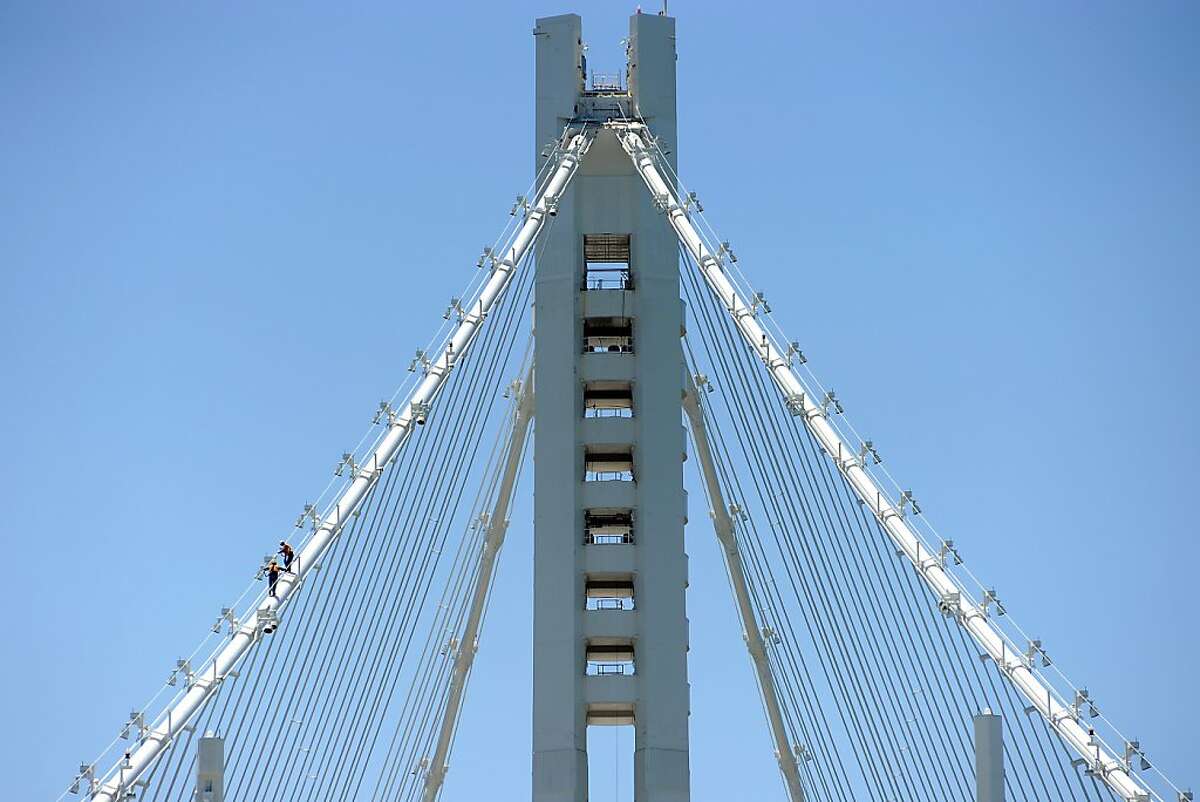 Workers walk up the suspension cable on the tower structure of the new eastern span of the Bay Bridge in Oakland, CA Saturday May 18th, 2013.