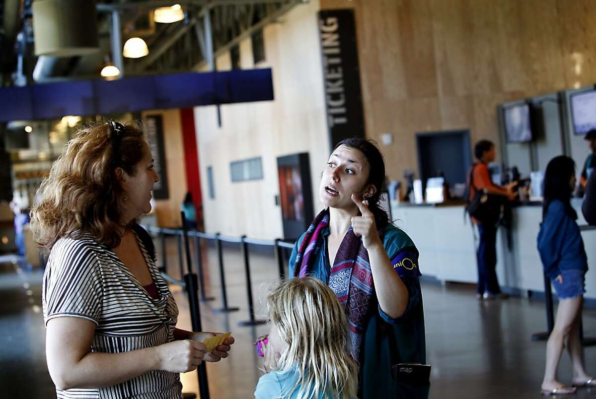 Jericha Senyak (cq), right, helps a visitor to the Exploratorium in San Francisco, Calif., Thursday, August 15, 2013. The Exploratorium is laying off some of its employees because of lower attendance than expected.