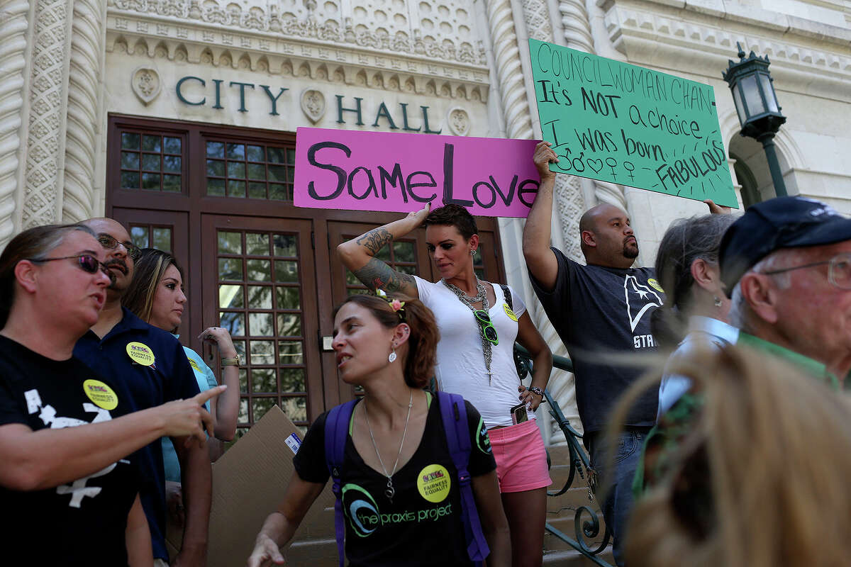 Andrea Moutria, left/center, and Alberto Barragan, right/center, get into place with signs for members of the Community Alliance for a United San Antonio to speak about the recording of District 9 City Councilwoman Elisa Chan's comments about homosexuality at City Hall in San Antonio on Friday, August 16, 2013.
