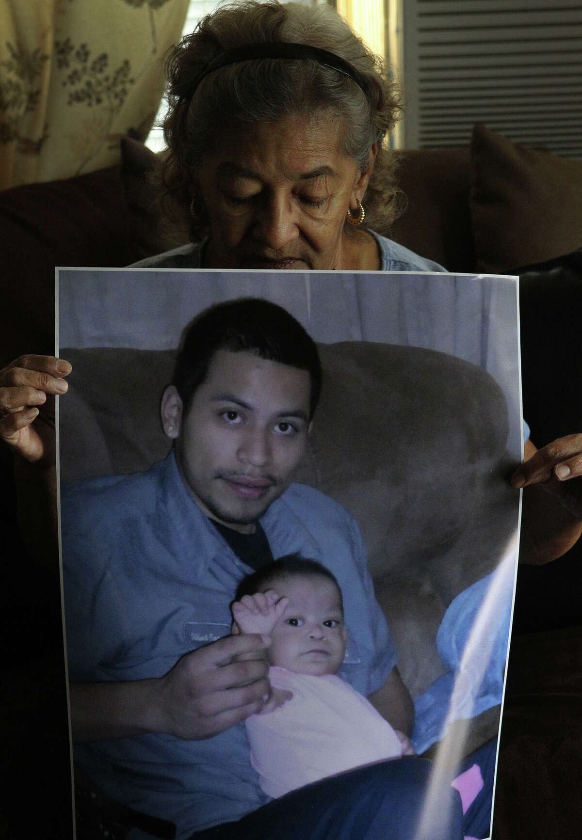 Stella Lopez holds a photograph Tuesday August 20, 2013 of her grandson Gilbert Ramos,25. Ramos was killed last Saturday night at the intersection of of Wallace street and General McMullen when a man fleeing from a different accident struck and killed Ramos. Jose Hernandez,56, has been charged with intoxication manslaughter after allegedly striking Ramos while Ramos was crossing the street. Hernandez has been convicted of driving while intoxicated four times since 1984. The little girl being held by Ramos is his daughter Azeriyah Huichan,1.