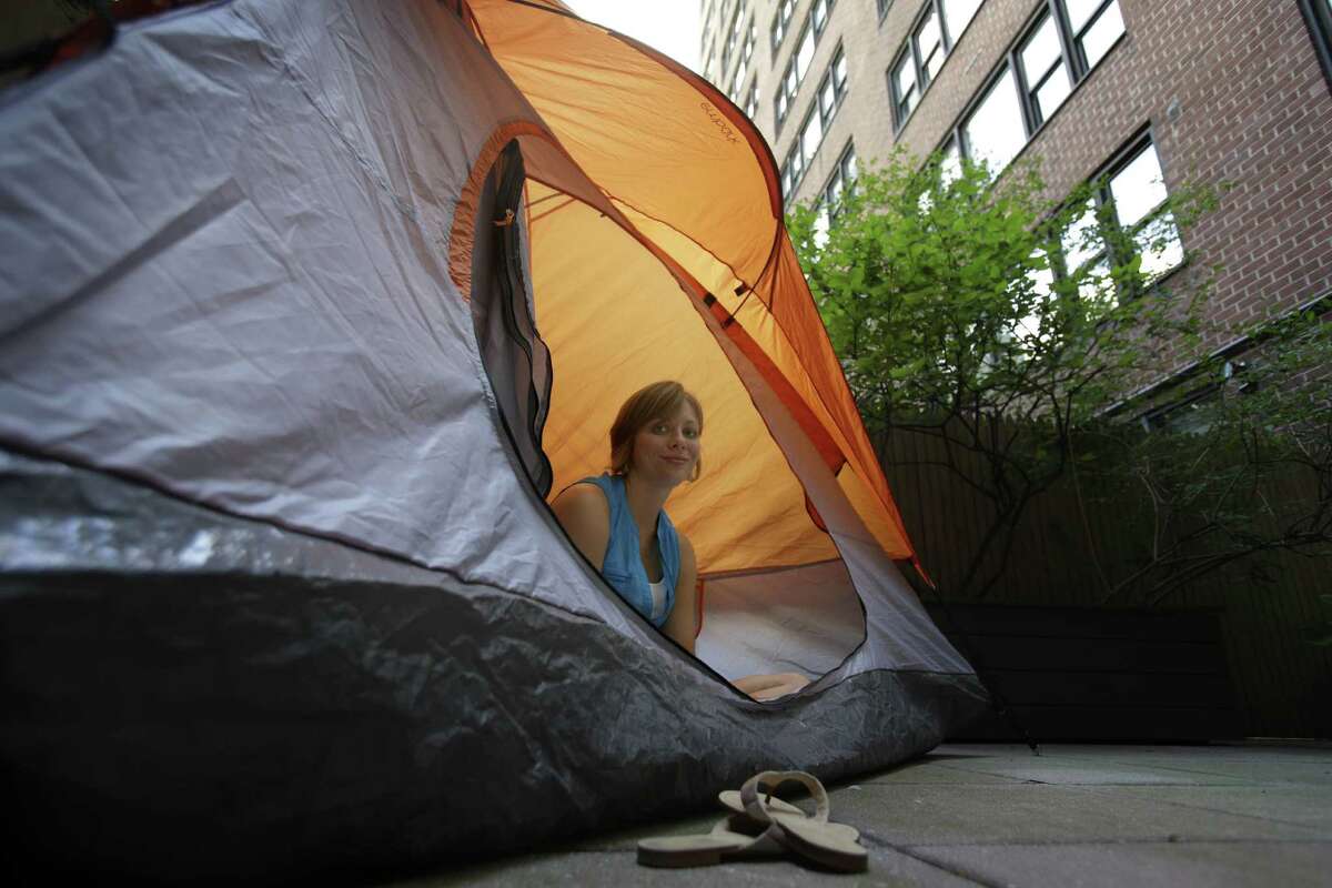 Kathleen Boyle poses for a picture in a tent on the patio of her room at the Affina Hotel in New York, Thursday, Aug. 15, 2013. A couple of New York City locales are offering an unusual option _ the chance to sleep outdoors, incredibly comfortably. It’s an urban take on “glamping,” where hotel comforts are taken outside. (AP Photo/Seth Wenig) ORG XMIT: NYSW202