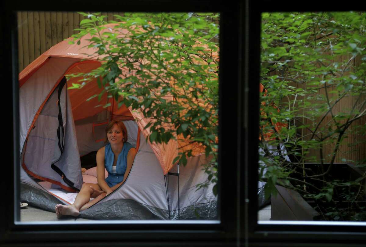 Kathleen Boyle poses for a picture in a tent on the patio of her room at the Affina Hotel in New York, Thursday, Aug. 15, 2013. A couple of New York City locales are offering an unusual option _ the chance to sleep outdoors, incredibly comfortably. It’s an urban take on “glamping,” where hotel comforts are taken outside. (AP Photo/Seth Wenig) ORG XMIT: NYSW205