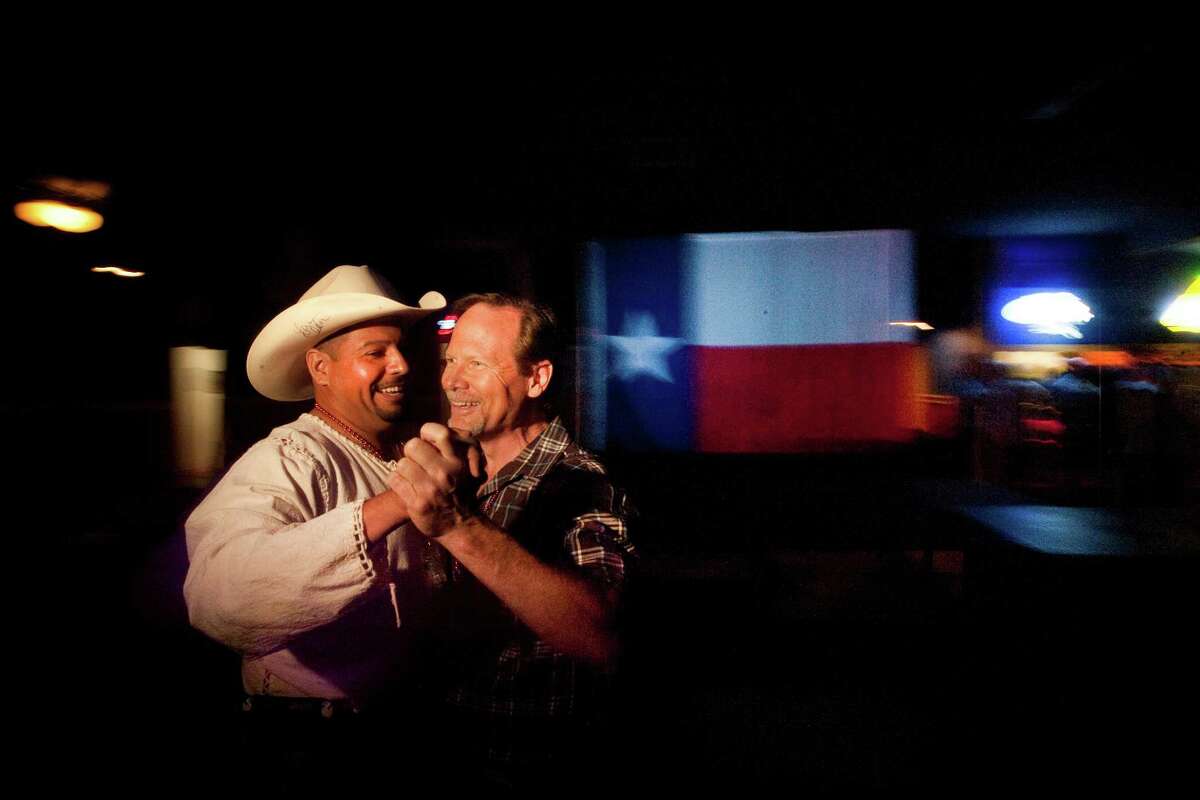 Jesse Vargas and Doug Paulsen dance at the Neon Boots Dancehall and Saloon, a country-style gay, lesbian and transgender bar located in the former home of the Esquire Ballroom at 11410 Hempstead Highway Thursday, Aug. 15, 2013, in Houston. The Esquire has gone through many transitions. It began as a plaice where Willie Nelson played a regular gig and wrote the song "Night Life" about the place. Patsy Cline used to sing there too. The hall eventually evolved into Latin dance clubs and now has gone back to its country roots. ( Johnny Hanson / Houston Chronicle )