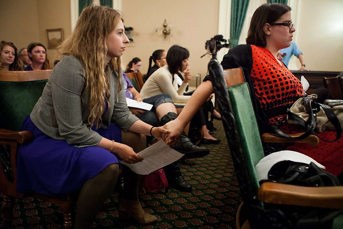 University of California, Berkeley students Sofie Karasek, left, and Aryle Butler, right, hold hands as they wait to testify about their experience with campus sexual assault before the Joint Legislative Audit Committee hearing at the State Capitol August 21, 2013 in Sacramento, California.
