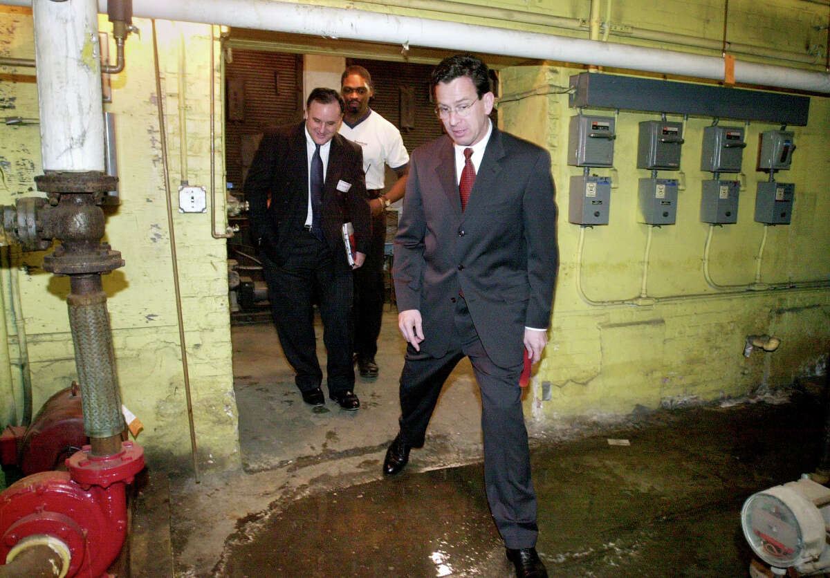 Stamford Mayor Dannel Malloy steps over a puddle of water in the boiler room of Rogers Elementary School during a tour of the Stamford, Conn. facilities in 2001. In the back are Al Barbarotta of the Stamford Public Schools Facilities Management, far left, and Robert Malcolm, head custodian.