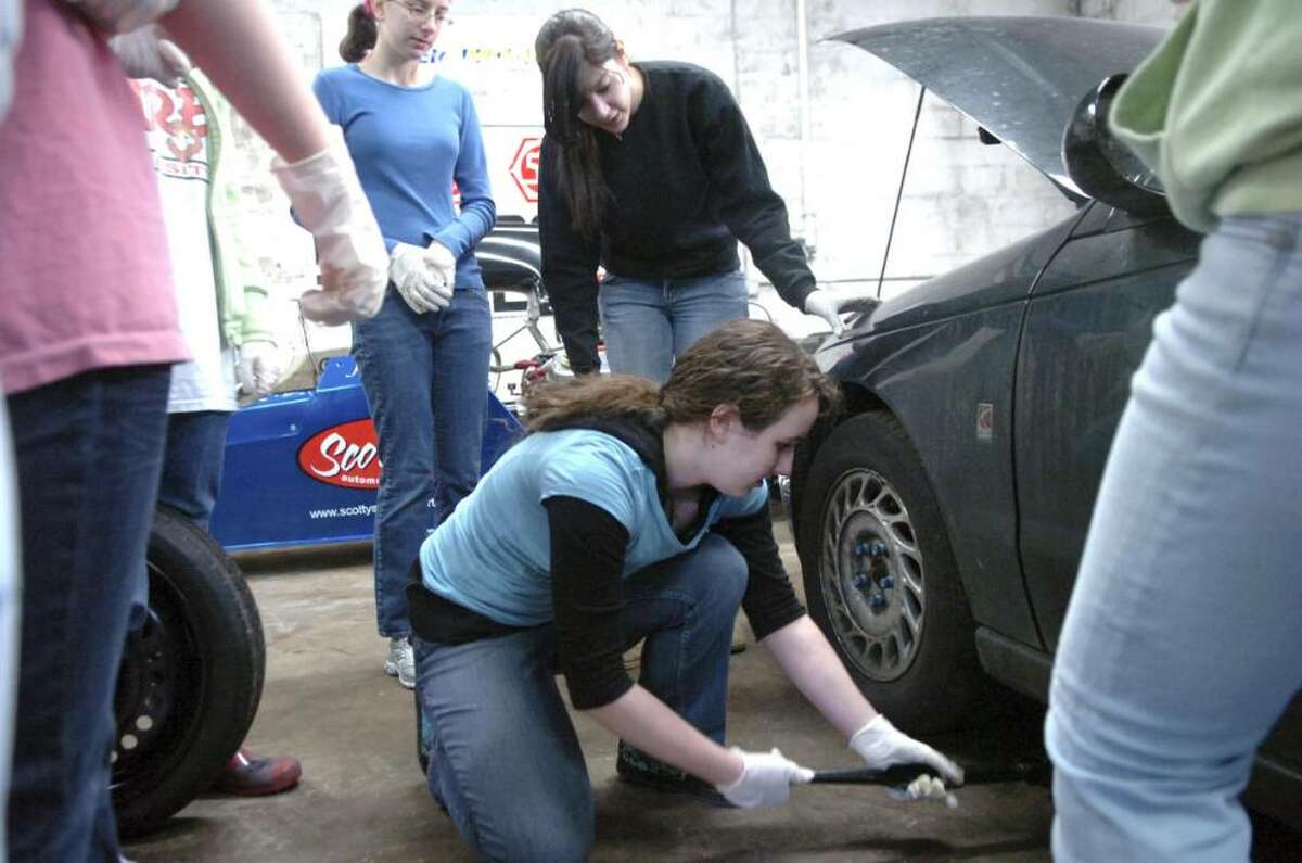 Stamford, Jan. 17, 2010. Jennifer Franze, 14, about to change a tire, instructed by Kaitlyn Sobeski. The girls scouts were getting together at Scotty's Motor Sports garage (26 Liberty Street, Stamford) to learn first hand how to change a flat tire, change oil, do a tune up, change brakes, and do basic auto maintenance.