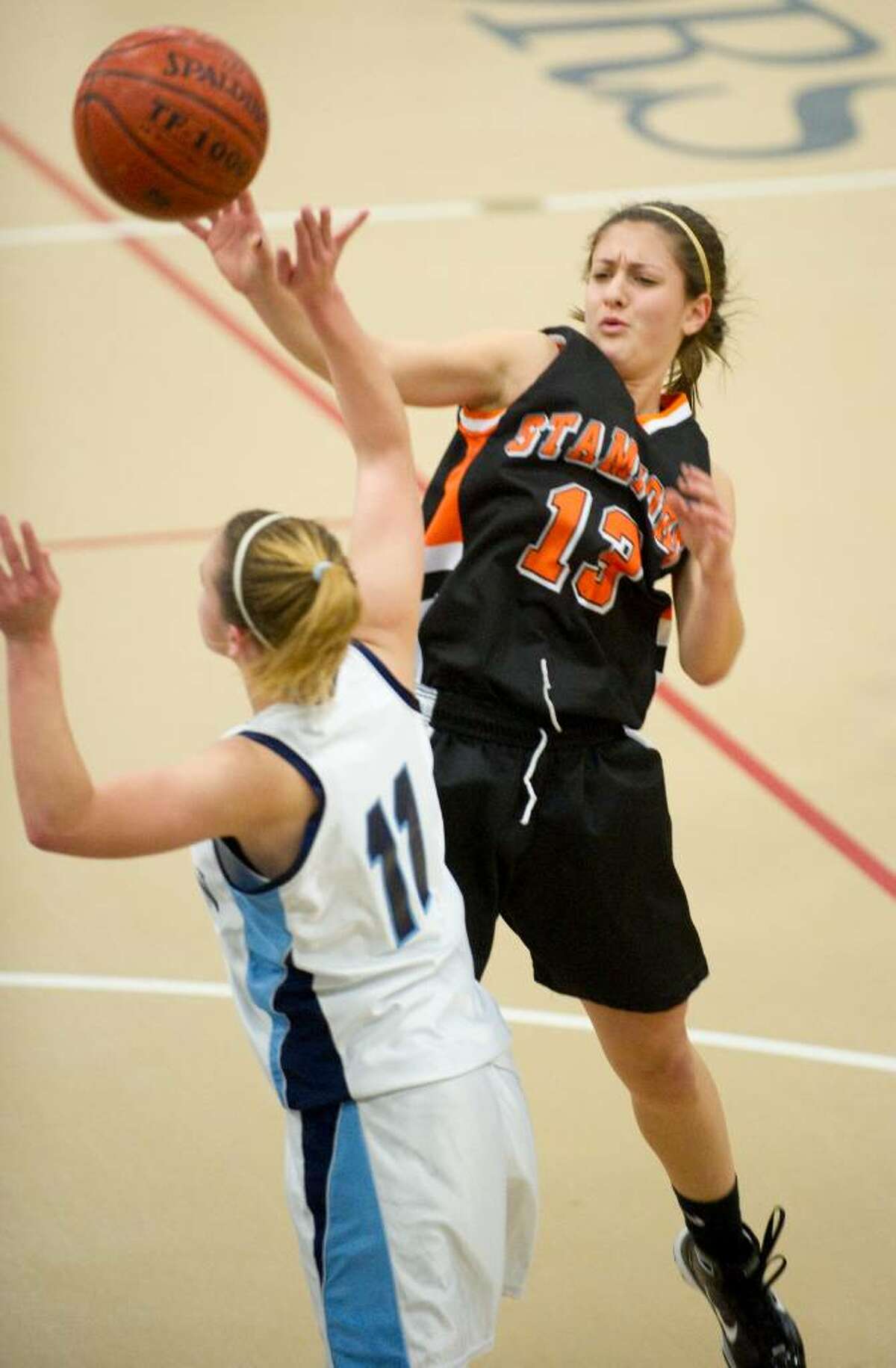 Stamford's Kelsey Cognetta, right, passes around Wilton's Stacey Peroka, left, during an FCIAC girls basketball game at Wilton High School in Wilton, Conn. on Thursday, Jan. 21, 2010.