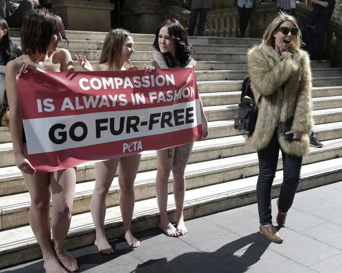A passer-by, right, appears to mock anti-fur protesters Tanya Ward, left, Zoe Crawford and Jacqui House, right, who have stripped to their underwear in an attempt to persuade clothing designers to stop using animal fur in Sydney, Australia, Wednesday, Aug. 21, 2013. The protestors from PETA, People for the Ethical Treatment of Animals, are protesting at Sydney Town Hall where a fashion festival is set to begin.