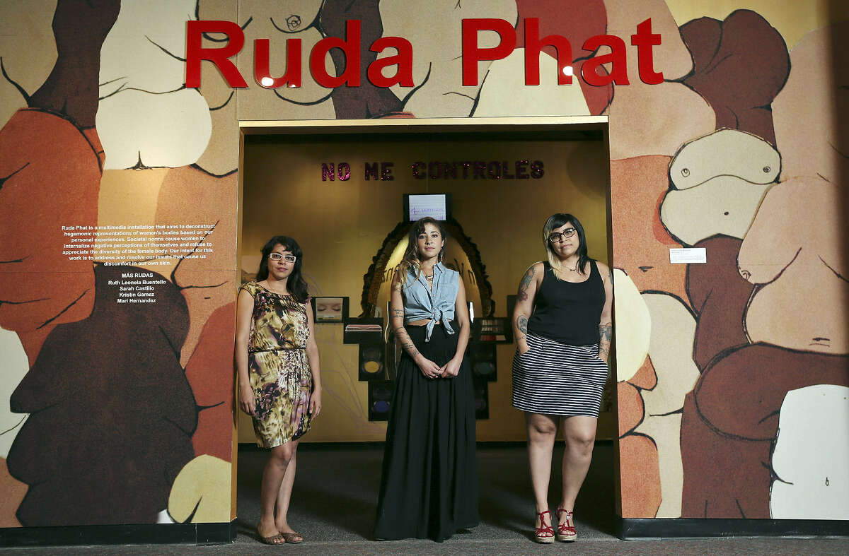 Chicana arts collective Mas Rudas members Sarah Castillo (from left), Kristin Gamez and Mari Hernandez stand at the entrance to their exhibit “Ruda Phat” at the Institute of Texan Cultures. Not pictured is Ruth Leonela Buentello.