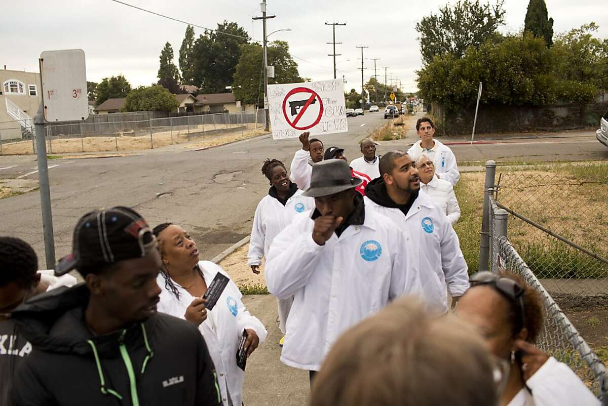 People wearing jackets that read "lifelines to healing" go out on a Friday night walk with others to pray, talk with residents about violence and gun buyback programs in East Oakland, Calif., Friday, August 9, 2013.