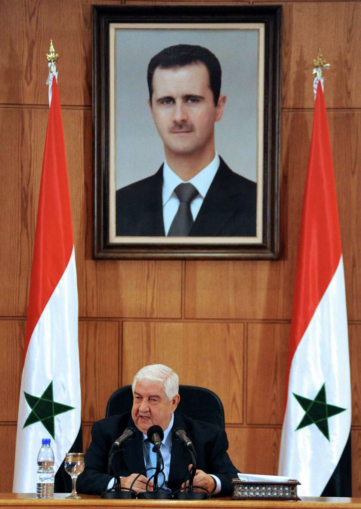 Syrian Foreign Minister Walid Muallem, shown under a portrait of President Bashar Assad, said Tuesday in Damascus that the government has defenses that would “surprise” the world.