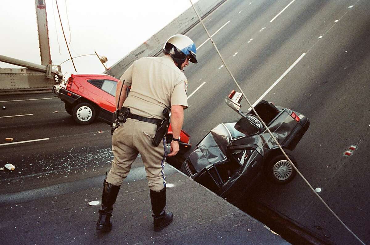 A California Highway Patrol officer checks the damage to cars that fell when the upper deck of the Bay Bridge collapsed onto the lower deck after the Loma Prieta earthquake in San Francisco. (Oct. 17, 1989.)
