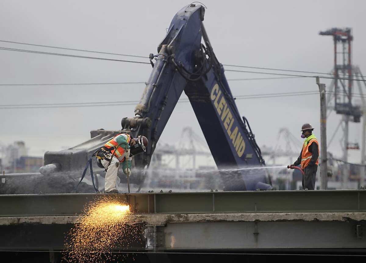 A demolition crew uses a torch to remove sections of the old bridge on the first day of construction work to connect the new eastern span of the Bay Bridge to Yerba Buena Island and Oakland, Calif. on Thursday, Aug. 29, 2013.
