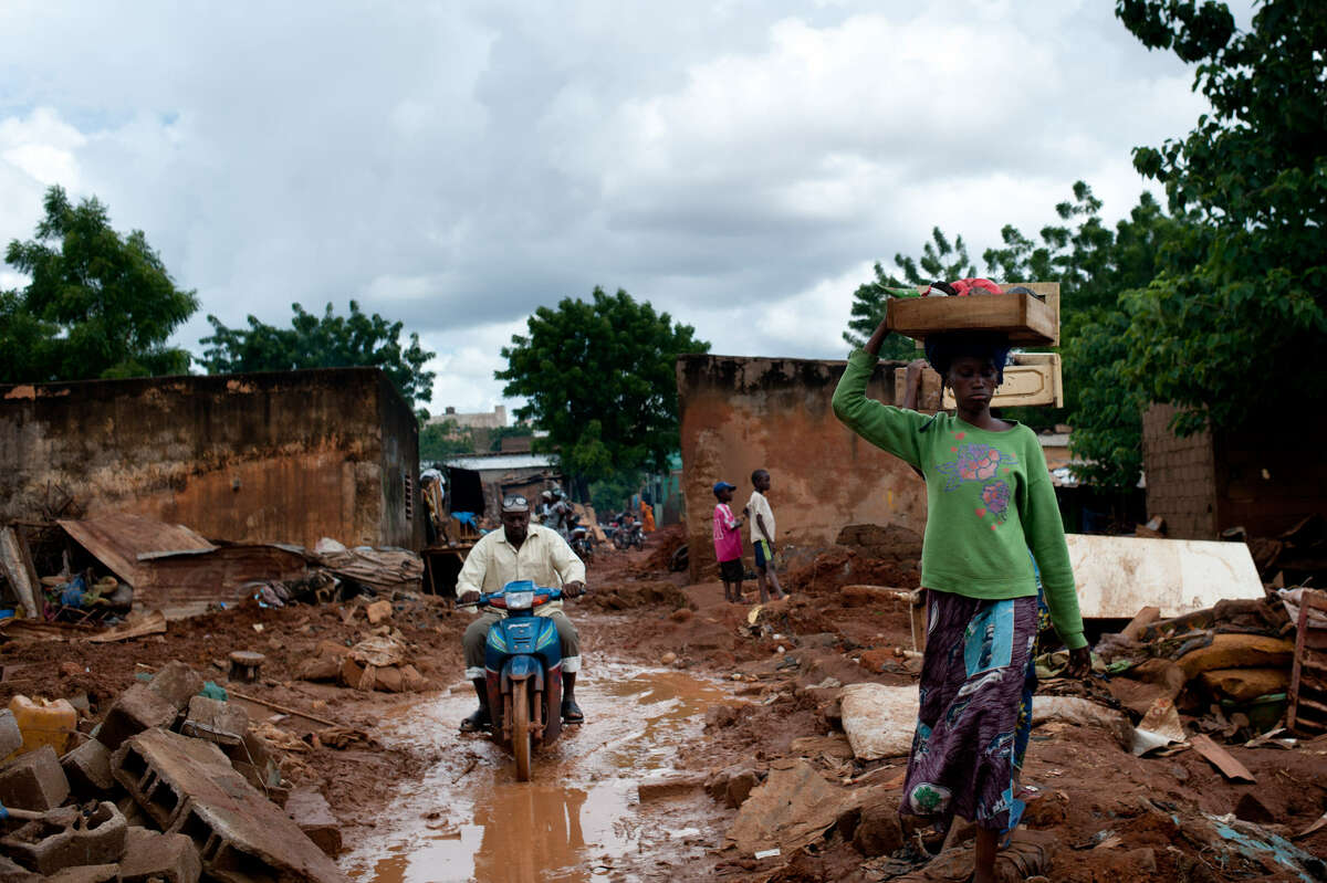 A woman carries what is left of her belongings after flooding caused many houses to collapse in the Banconi neighborhood of Bamako, Mali.