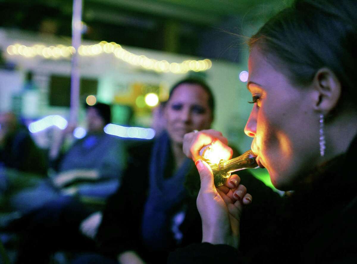 FILE - In this in Dec. 31, 2012 file photo, Rachel Schaefer of Denver smokes marijuana on the official opening night of Club 64, a marijuana-specific social club, where a New Year's Eve party was held, in Denver. According to new guidance being issued Thursday, Aug. 29, 2013 to federal prosecutors across the country, the federal government will not make it a priority to block marijuana legalization in Colorado or Washington or close down recreational marijuana stores, so long as the stores abide by state regulations. (AP Photo/Brennan Linsley) ORG XMIT: COBL503