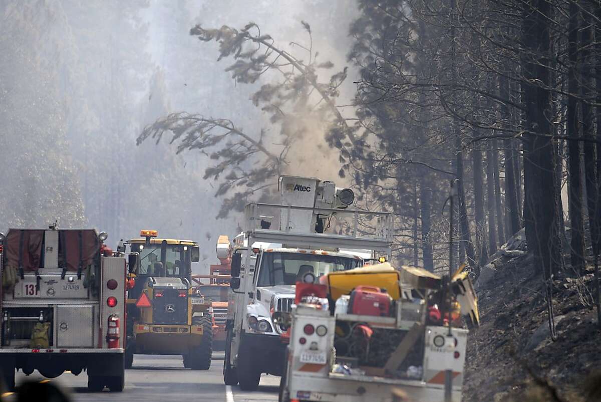 Workers cut trees burn by the Rim Fire along Highway 120 near Yosemite National Park, Calif., on Wednesday, Aug. 28, 2013. The giant wildfire burning at the edge of Yosemite National Park is 23 percent contained, U.S. fire officials said Wednesday. (AP Photo/Jae C. Hong)
