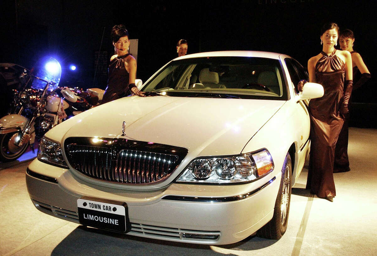Models pose with Ford Motor Company's Lincoln Town Car Limousine during a media unveiling in Seoul Tuesday, Oct. 29, 2002. The Lincoln Town Car, priced at 82 million Korean won ($65,600), is equipped with V8 SOHC (4,600cc) engine. (AP Photo/Ahn Young-joon)