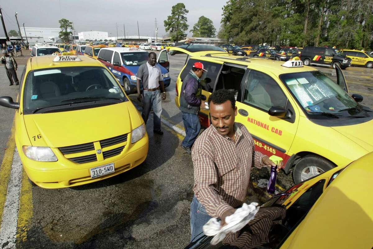 Sahlu Aberra cleans the back window of his cab at the Houston airport taxi staging area near George Bush Intercontinental Airport Tuesday, Jan. 22, 2008, in Houston. ( Brett Coomer / Chronicle )
