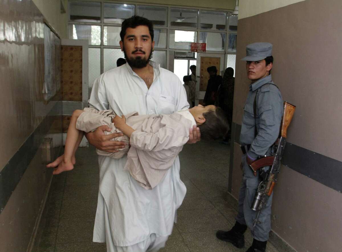 An Afghan doctor carries a boy in a hospital after the suicide bomb blast in Kandahar province. The explosives were detonated near a police checkpoint and a bank.