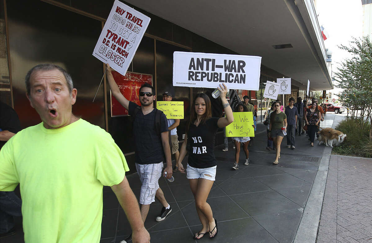 Anti-war protesters make their way along Alamo Street near Rivercenter mall Saturday. About a dozen people carried signs and chanted slogans such as “no war” as they walked along downtown.