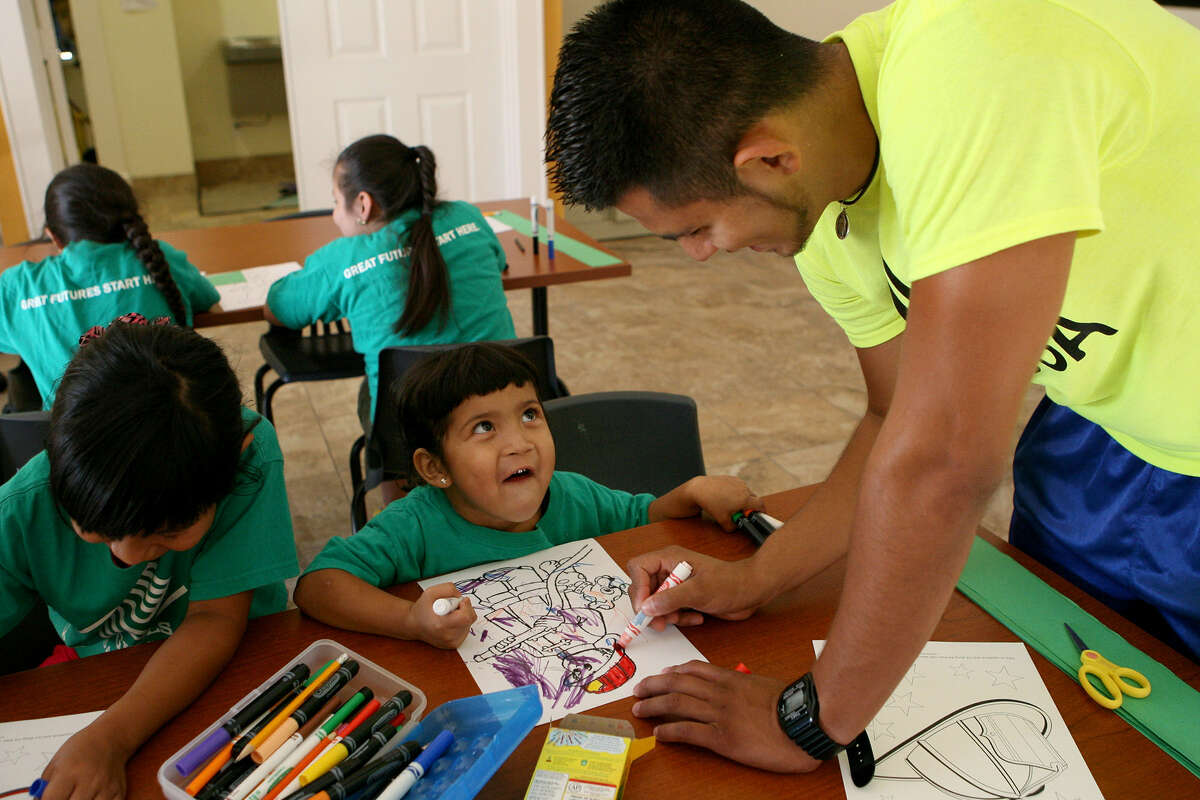 Jennifer Hernandez, 3, looks up to Humberto Campos of the Boys & Girls Clubs of San Antonio, which have expanded to meet demand.