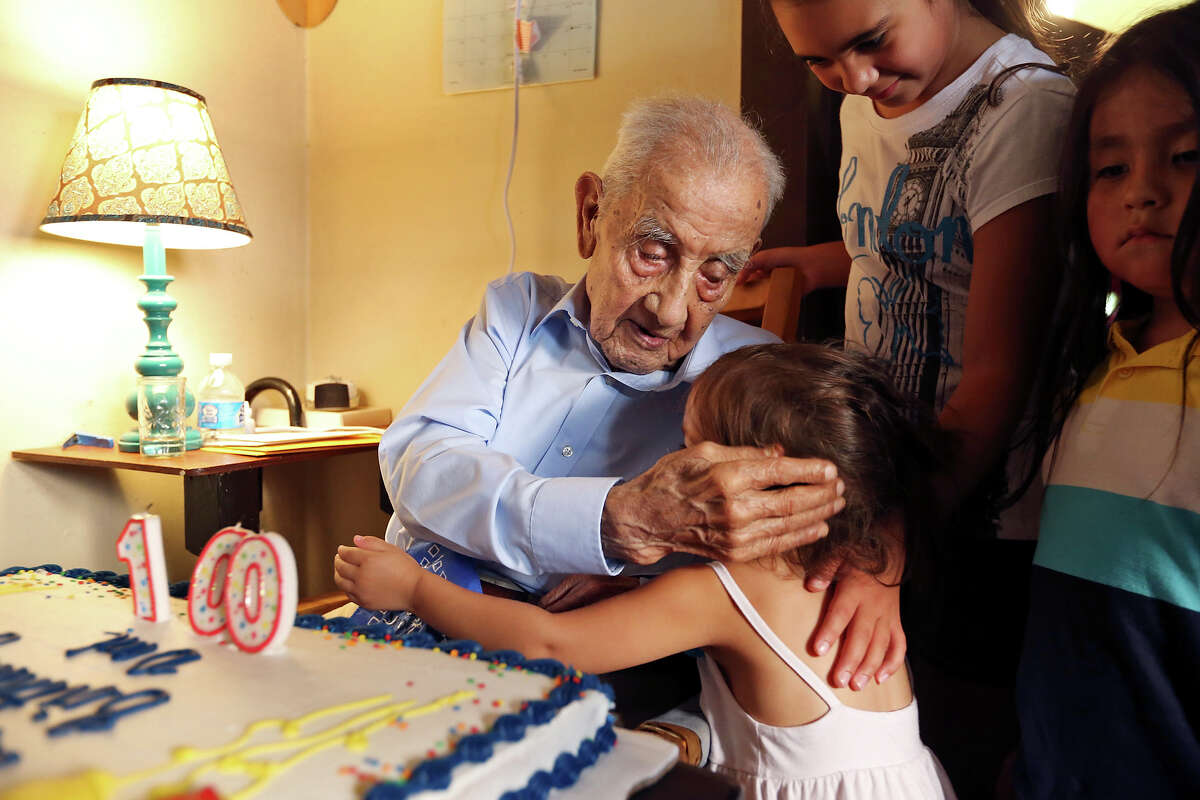 Alfonso Morales, 100, hugs great-granddaughter Abigail Garcia, 2, as great-granddaughter Lauren Crane, 9, (top) and great-grandson Neven Garcia, 5, look on during his 100th birthday party last month.