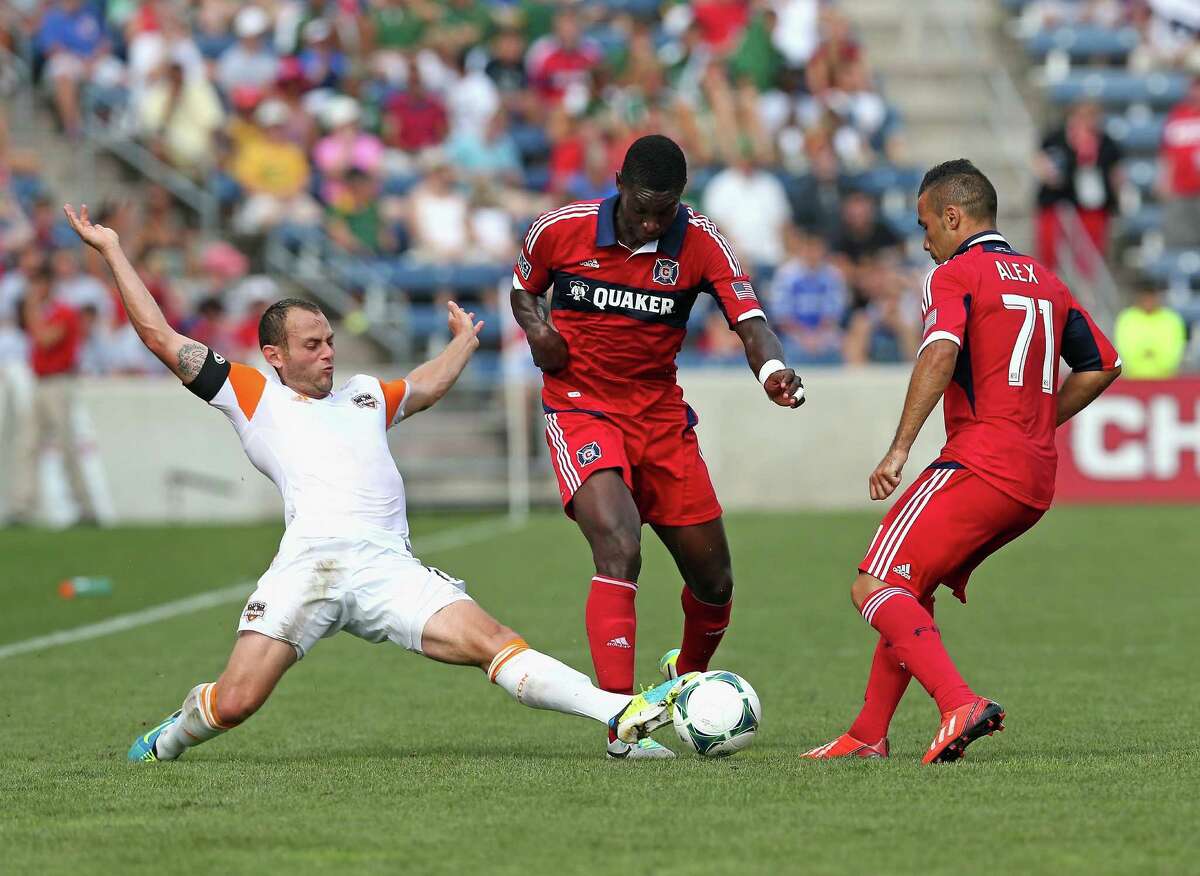 BRIDGEVIEW, IL - SEPTEMBER 01: Brad Davis #11 of the Houston Dynamo kicks the ball between Jalil Anibaba #6 and Alex #71 of the Chicago Fire during an MLS match at Toyota Park on September 1, 2013 in Bridgeview, Illinois.