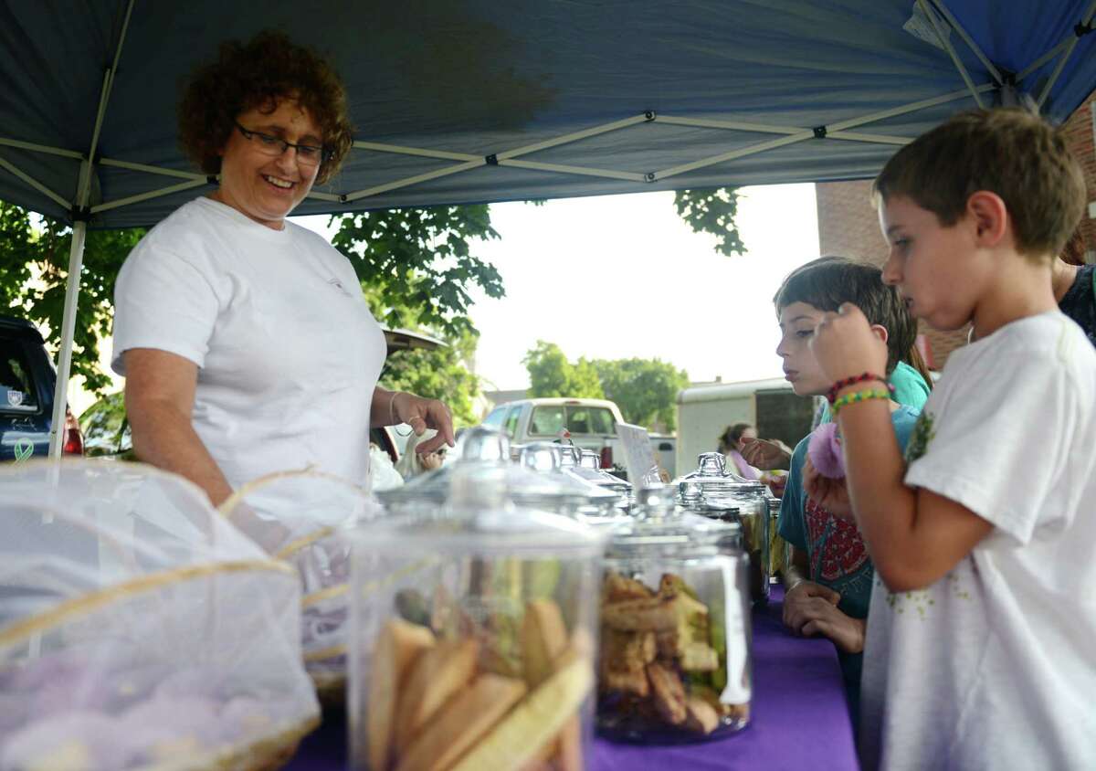 Stephanie Schneiderman, of Sandy Hook, sells biscotti to Oliver Charles, far right, 8, of Sandy Hook, and Leo Brosnan, 10, of Newtown, at the farmers market at Fairfield Hills in Newtown, Conn. on Thursday, Sept. 3, 2013. Schneiderman, a former teacher, has been running her company, Biscotti Etc., since February and sells her product locally at area farmers markets.