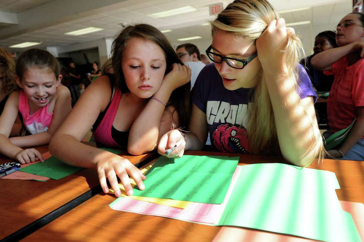 Freshmen Breanna Mysliwiec, 14, center, and Karley Culliton, 14, right, work on an exercise during Freshman Academy on Wednesday, Aug. 28, 2013, at Lansingburgh High School in Troy, N.Y. At left is Samantha Culliton, 7, Karley's sister. The school's new Freshman Academy aims to improve student performance as they transition to high school. (Cindy Schultz / Times Union)