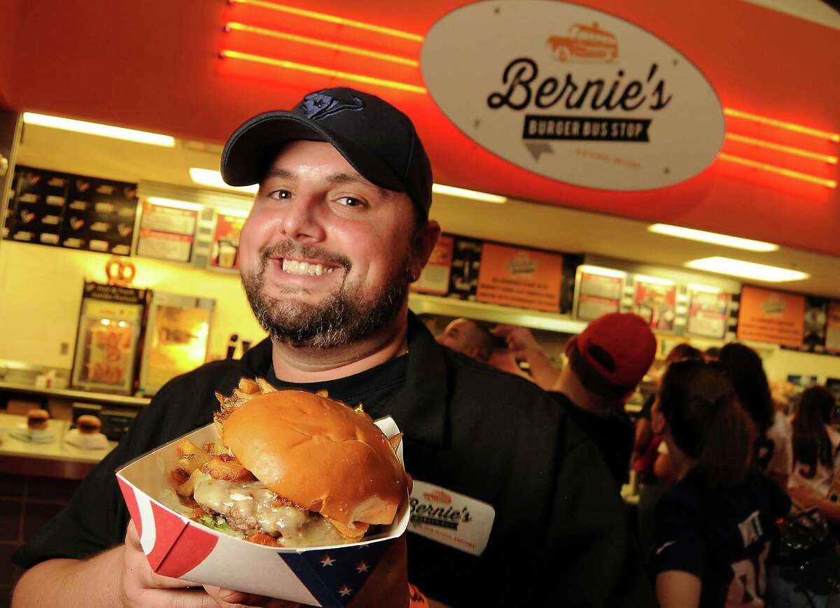 Owner Justin Turner holds a "cheerleader" burger at the new Bernie's Burger Bus concession at Reliant Stadium. (Dave Rossman photo)