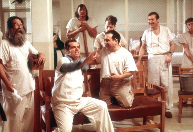 A group of men in white uniforms laughing and interacting in a communal room.