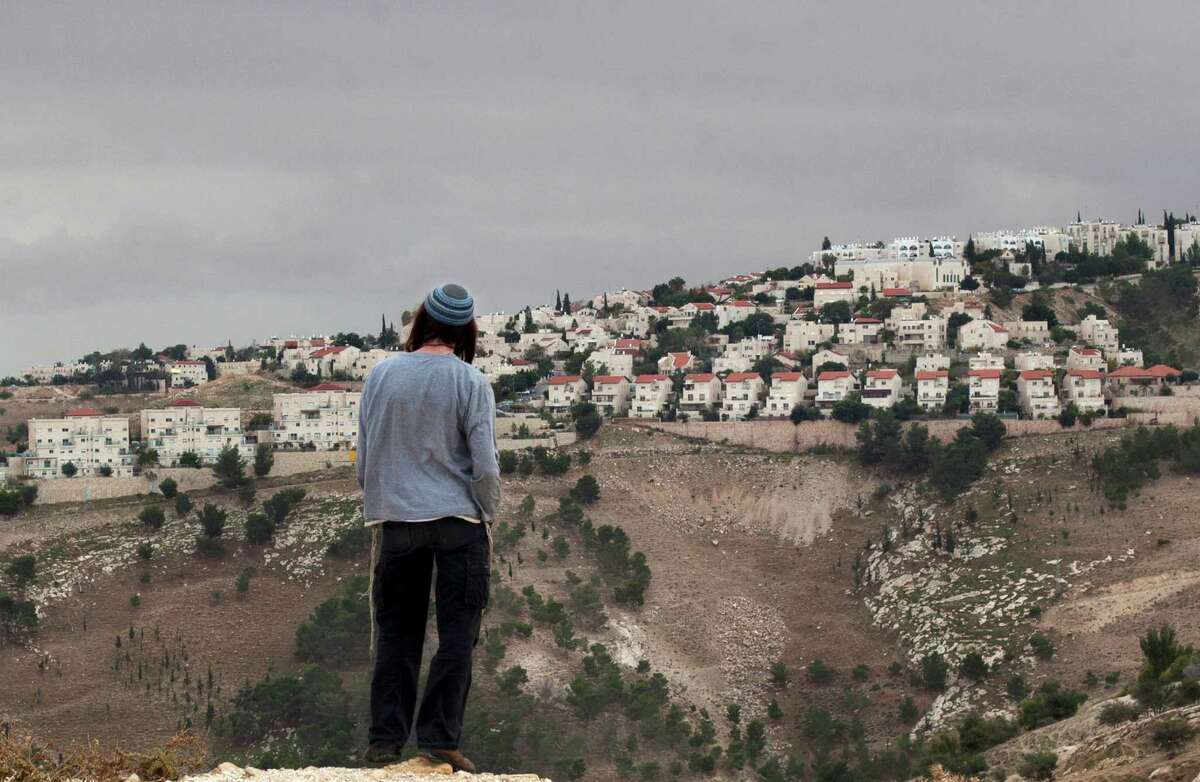 FILE - In this Wednesday, Dec. 5, 2012 file photo A Jewish settler looks at the West bank settlement of Maaleh Adumim, from the E-1 area on the eastern outskirts of Jerusalem. Israel has proposed leaving intact dozens of Jewish settlements and military bases in the West Bank as part of a package to establish a Palestinian state in provisional borders, a Palestinian official told The Associated Press on Wednesday, Sept. 4, 2013, in the first detailed glimpse at recently relaunched peace talks. (AP Photo/Sebastian Scheiner, File)