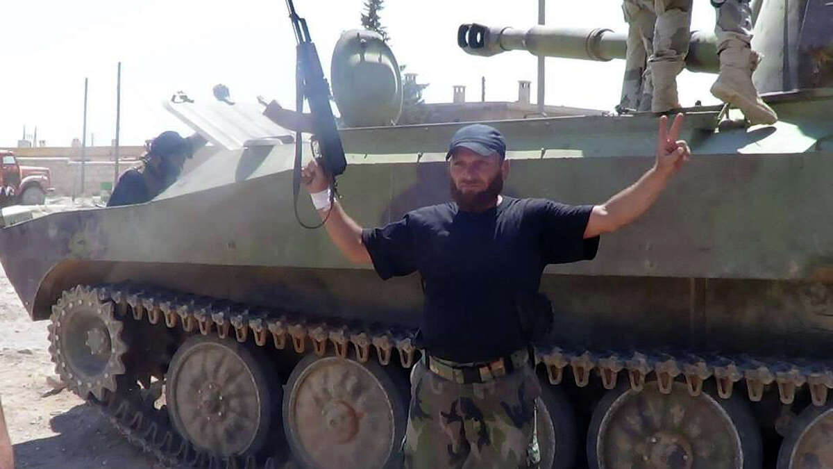 In this citizen journalism image provided by The Committee of Jabal al-Zawiyah, Jisr el-Sheghour, Maarat al-Naaman, Idlib, which has been authenticated based on its contents and other AP reporting, a Free Syrian army fighter holds his weapon as he poses for a photograph in front of a military tank in Idlib province, Syria, Wednesday, Sept. 4, 2013. (AP Photo/Aleppo Media Center, AMC)