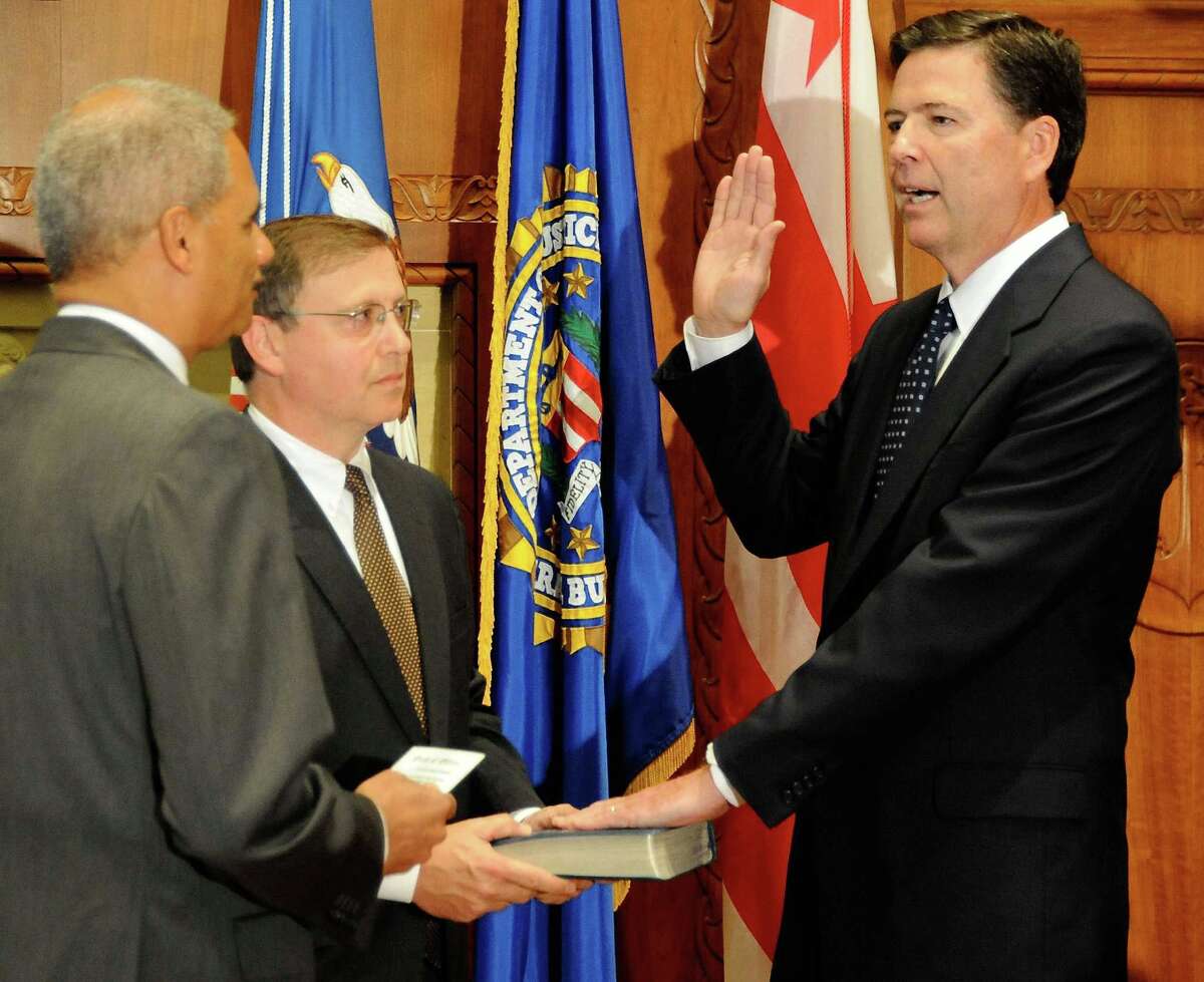 James B. Comey of Westport, right, is sworn in as FBI director Wednesday by U.S. Attorney General Eric Holder. Chuck Rosenberg, senior counselor to Comey, holds the Bible.