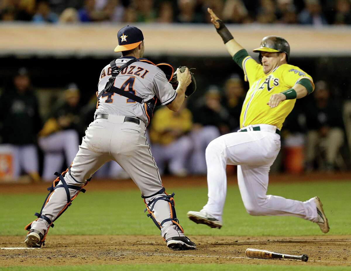 Astros catcher Matt Pagnozzi, left, can't get the tag on Stephen Vogt as he scores in the eighth. Astros manager Bo Porter was ejected after arguing the call.