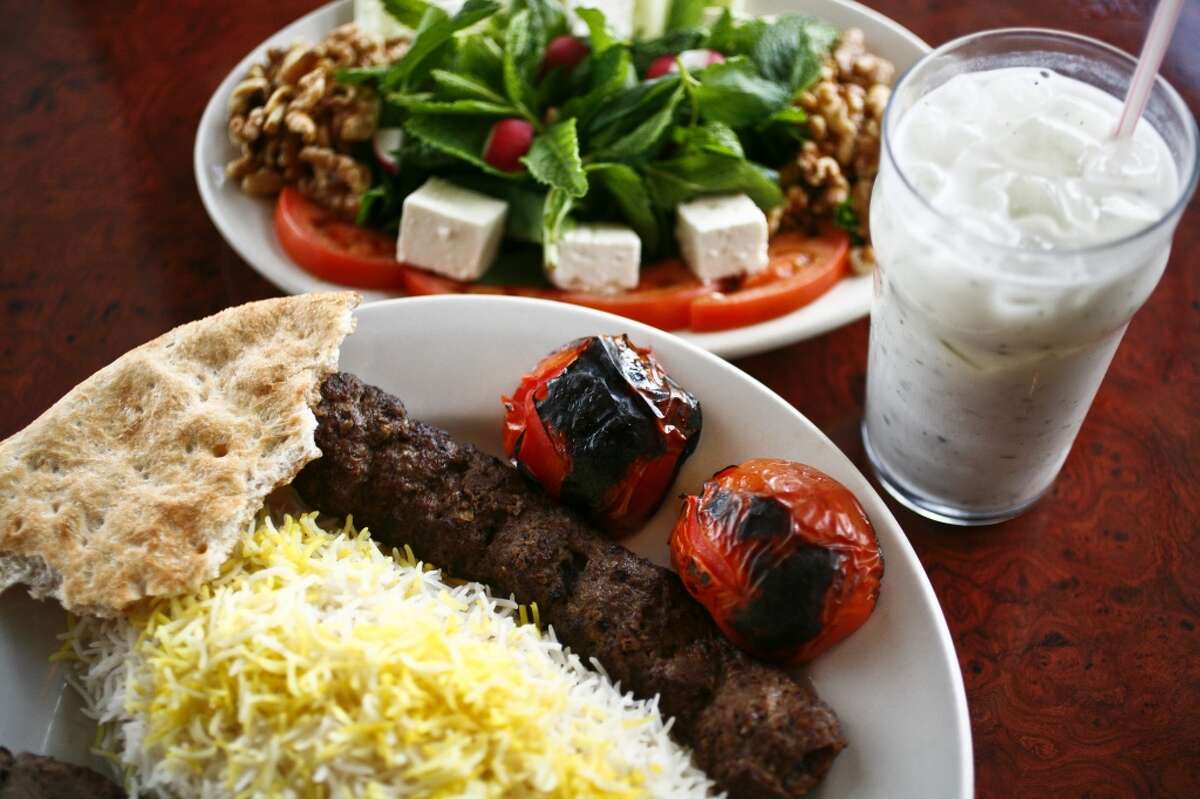 The Sultani, a skewer of beef Kubideh and a skewer of beef Barg along with white rice, the Special Herb Plate and a cup of Doogh, a yogurt drink, at Kasra