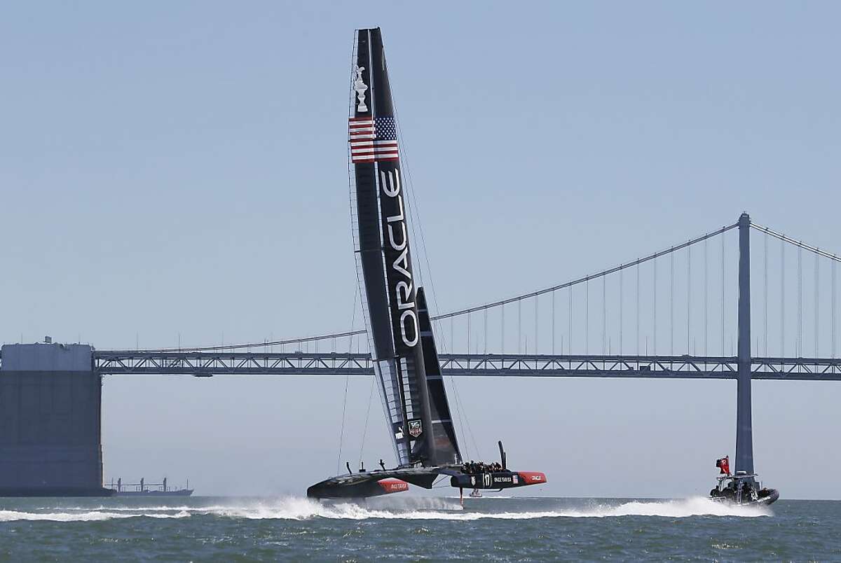 Oracle Team USA crosses the finish line with San Francisco-Oakland Bay Bridge visible in the distance during training for the America's Cup sailing event Thursday, Sept. 5, 2013, in San Francisco. The first races between Oracle Team USA and Emirates Team New Zealand are on Saturday. (AP Photo/Eric Risberg)