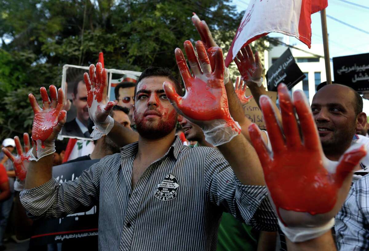 Lebanese pro-Syrian regime supporters, with their hands painted in red to symbolize blood, attend a demonstration against a possible military strike in Syria, near the U.S. Embassy in Aukar, east of Beirut, Lebanon, Friday, Sept. 6, 2013. The prospect of a U.S.-led strike against Syria has raised concerns of potential retaliation from the Assad regime or its allies. The State Department ordered nonessential U.S. diplomats to leave Lebanon over security concerns and urged private American citizens to depart as well. (AP Photo/Hussein Malla)