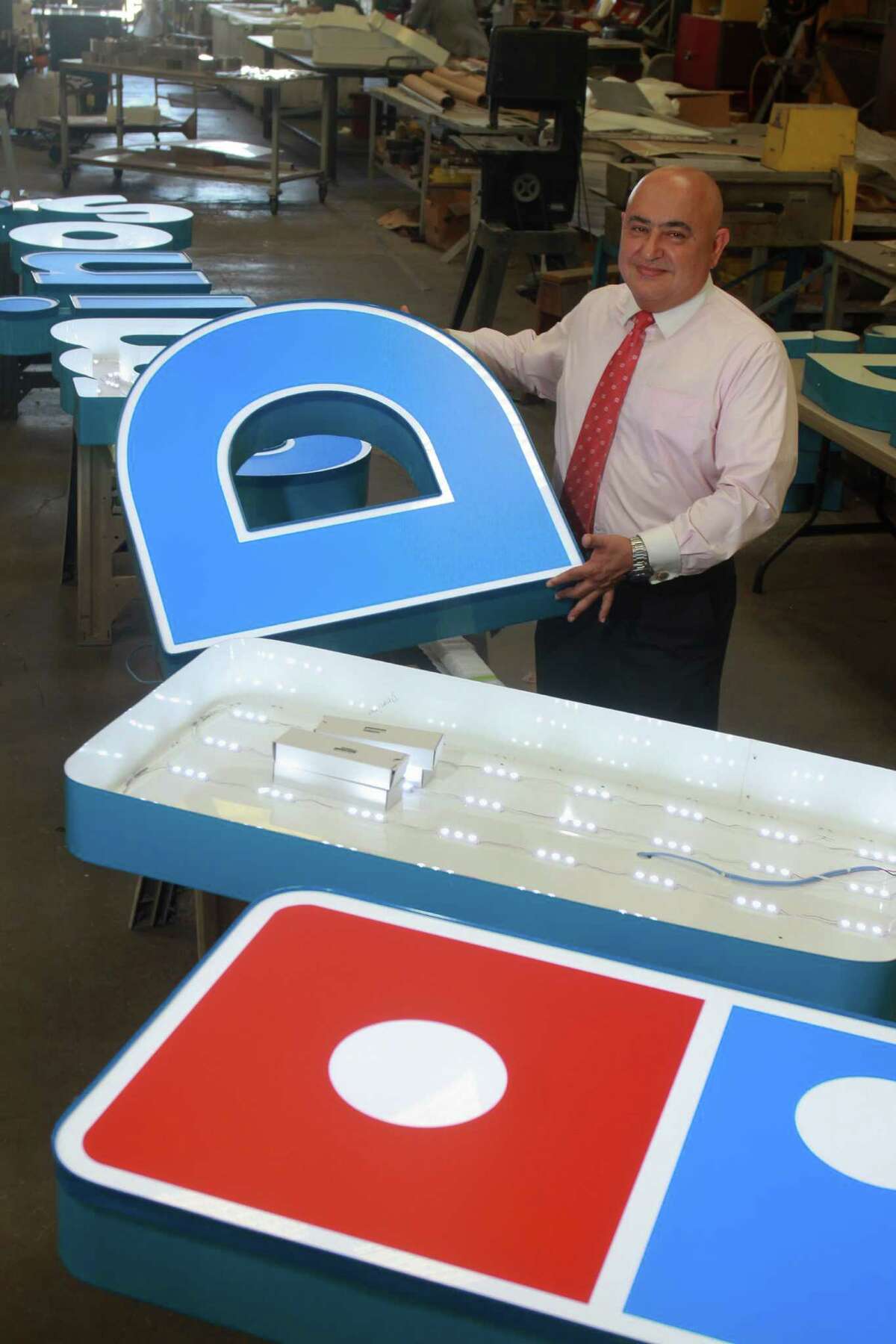 Joe Minavi of Sparkle Sign Co., with a Domino Pizza sign that is in production.